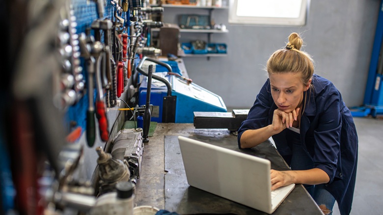 A woman mechanic working on a laptop in a workshop
